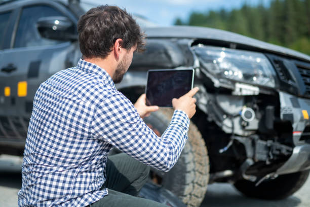 Insurance adjuster inspecting car. Male Insurance adjuster inspecting car using digital tablet. broken digital tablet note pad cracked stock pictures, royalty-free photos & images