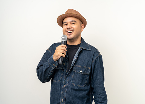 Happiness young asian man singing song. Artist vocalist singer on isolated background. Confident man public speaking talking with microphone in studio.