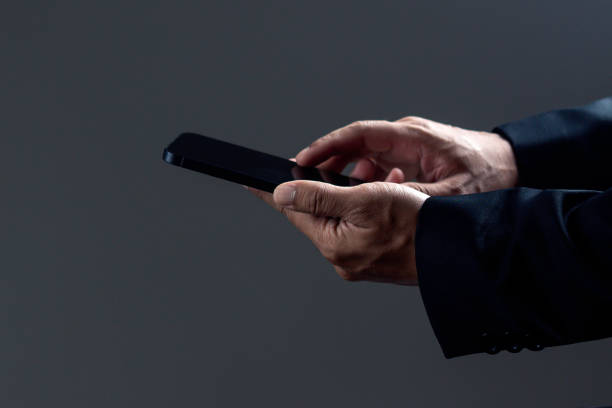 istock Businessman is touching smartphone against dark background. 1687768364