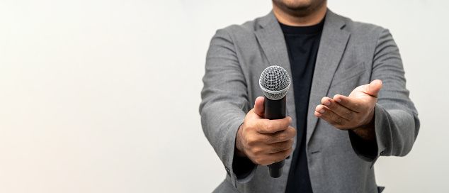 Close up businessman speaker hand holding High quality dynamic microphone and singing song or speaking talking with people on isolated white background. Male testing microphone voice for interview