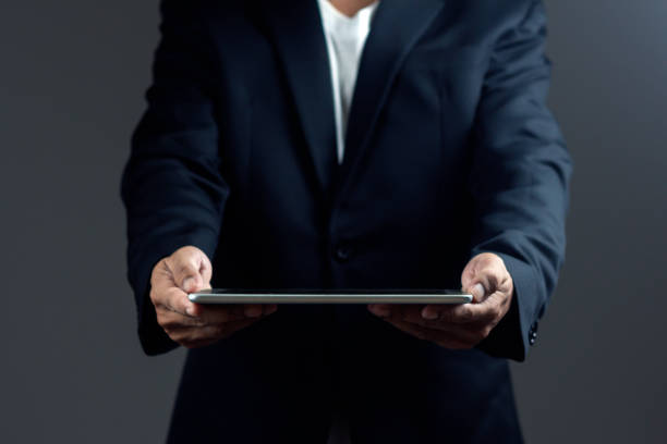 istock Businessman is holding digital tablet against dark background. 1687769427