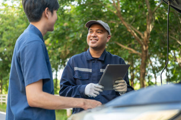 Professional mechanic talking in a conversation with the car owner, explaining the car's issue and the methods of repair. Checking the broken engine and damage as listed. Repair car outside service. mecánico profesional hablando en una conversación con el propietario del automóvil, explicando el problema del automóvil y los métodos de reparación. comprobación del motor roto y el daño como se indica. reparación de coche fuera del servicio.