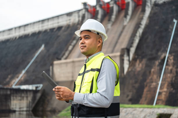 Professional asian maintenance engineer man with safety helmet in construction site dam with hydroelectric power plant and irrigation. Manager engineer man working at project big building.