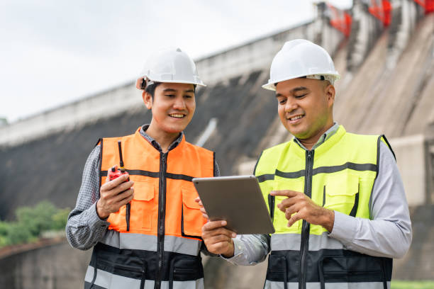 istock Confident asian two maintenance engineers man inspection discussstion with tablet at construction site dam with hydroelectric power plant and irrigation. Team engineer man working at project 1687771611