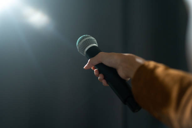 istock Close up woman hand holding High quality dynamic microphone and singing song or speaking talking with people on isolated white background. Woman testing microphone voice for interview 1687774331