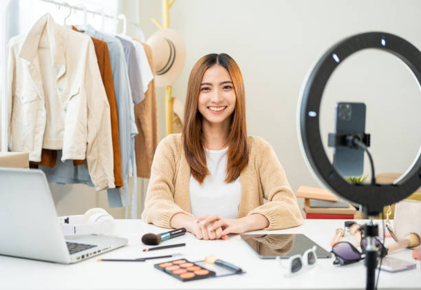 istock Young beautiful asian woman vlogger live broadcasting cosmetic makeup tutorial content looking at camera. Influencers with various cosmetic recording video review sharing on social media 1687790186