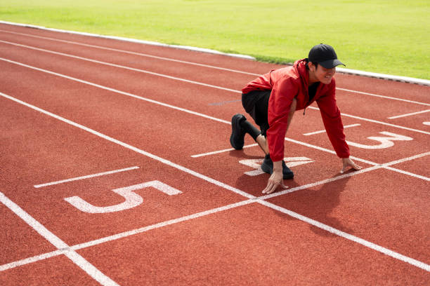 istock Young handsome indian man doing start pose before running exercise on track in sport stadium. Challenge race of athletes running in the starting point. Young asian man in sport athlete uniform 1687790254