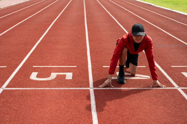 istock Young handsome indian man doing start pose before running exercise on track in sport stadium. Challenge race of athletes running in the starting point. Young asian man in sport athlete uniform 1687790275