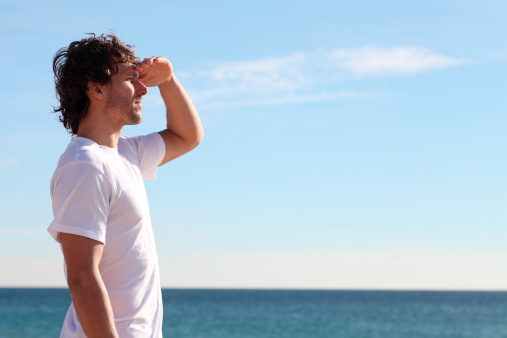 Man watching the sea with his hand in the forehead