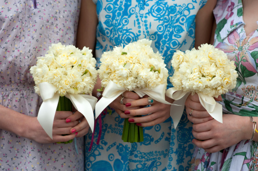 three daffodil wedding bouquets held by bridesmaids in vintage dresses