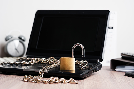 laptop with chain and unlocked padlock, computer and data security concept.