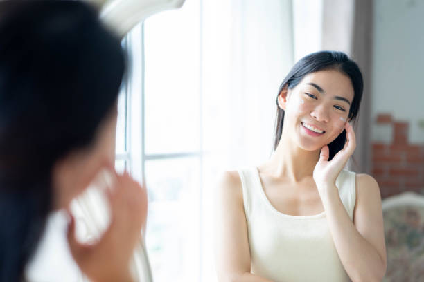 istock Young asian woman applying moisturizer on her face. Daily self-care routine. 1687900667