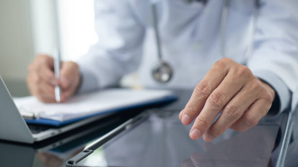 istock Medicine doctor working on digital tablet and laptop computer searching the information with medical document on table, close up. Doctor writing prescripetion and filling health insurance document 1687901249