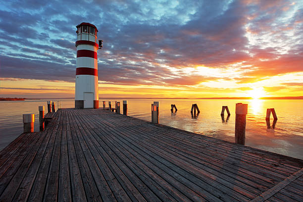 phare au coucher du soleil sur l'océan - beach sunrise waterbreak sea photos et images de collection