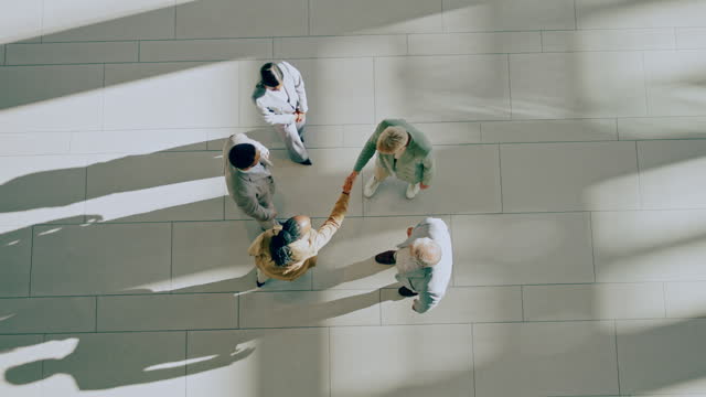 Above, handshake and group of business people welcome together and meeting in corridor for partnership or collaboration. Professional, deal and corporate team of employees in an office shaking hands