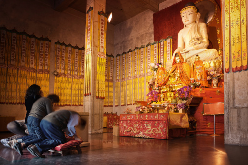 Budists praying infront of an ancient white Jade Budha statue in a temple