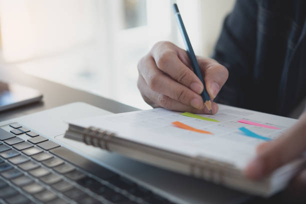 istock Event planner timetable agenda plan on year 2023 schedule event. Business man checking timetable, taking note on calendar planner notebook on office table. Calendar event plan, work planning 1687952685