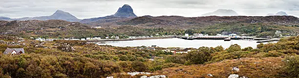 Panorama featuring the coastal Scottish village of Lochinver on a rainy Autumn day. The Suilven mountain can be seen in the background.