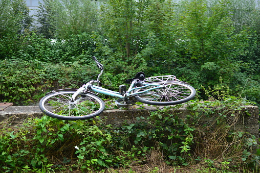 Leuven, Vlaams-Brabant, Belgium - September 17, 2023: stolen and abandoned woman's bicycle along a riverbed on a remote road. the solution, the answer is then, avoid these places and an official traffic sign in this street prohibits walking and cycling!
