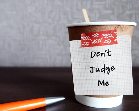 Paper coffee cup with handwritten note DON'T JUDGE ME, concept of  judging less, accept more, avoid judging someone else mistakes to avoid realize our own