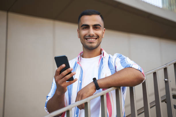 istock Handsome middle eastern man holding mobile phone shopping online looking at camera on urban street 1688005914