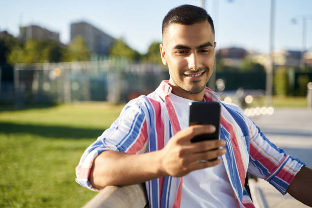 Young smiling Iranian man smiling happy using smartphone at the city