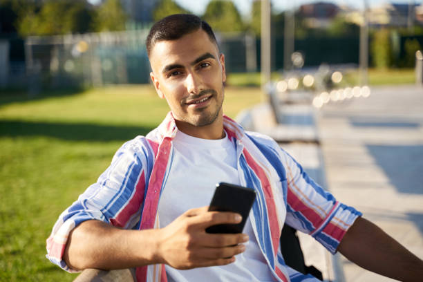 istock Smiling middle eastern man using mobile app shopping online sitting on bench 1688005941