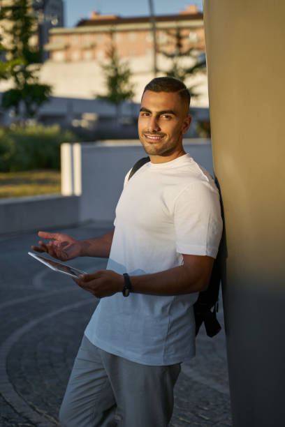 istock Smiling middle eastern man using digital tablet looking at camera on the street 1688007559