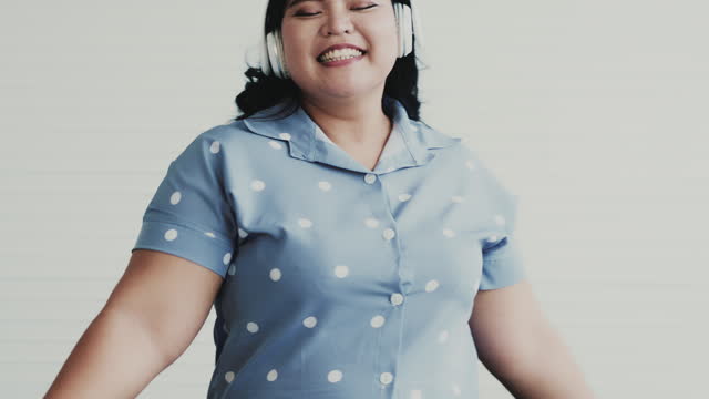 An attractive overweight woman singing and dancing in the living room