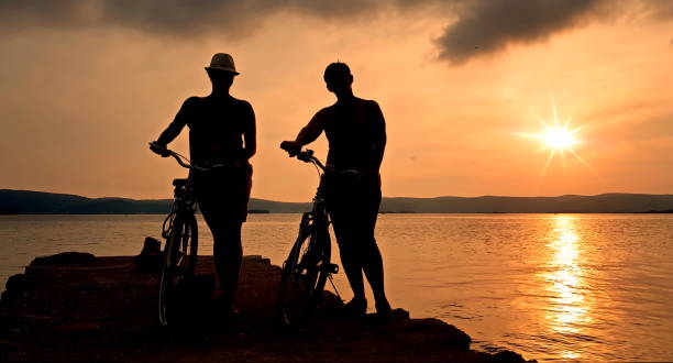 istock Silhouette of two women with bicycles 1688044066