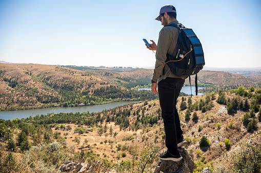 Man exploring and hiking in mountains with smartphone powered by solar cells