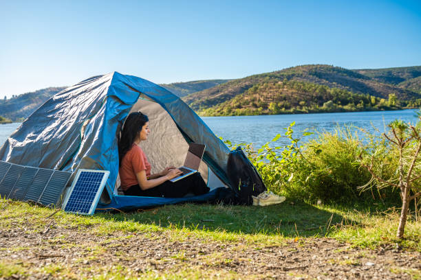 istock Young travel woman relax and  using laptop computer work remotely anywhere using internet connected to portable solar panel charging 1688054356