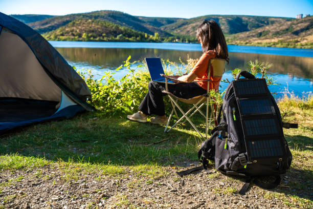 istock Young travel woman relax and  using laptop computer work remotely anywhere using internet connected to portable solar panel charging 1688064220