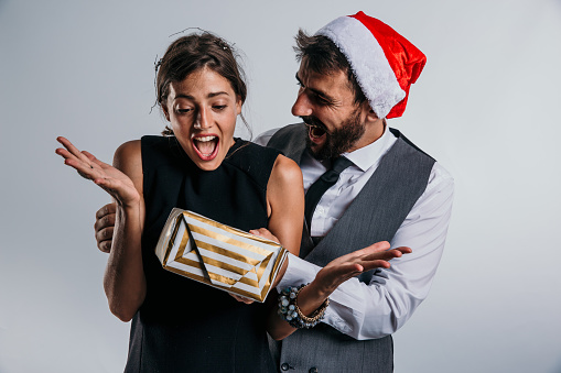 A business-savvy couple takes a moment to revel in the joy of the New Year, donning Santa hats and an array of beautifully wrapped presents in a studio.