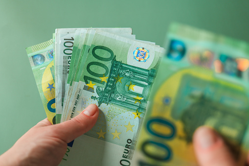 salario de una mujer. Billetes en euros en las manos sobre fondo verde. Ingresos de las mujeres en los países europeos photo