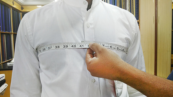 Closeup of tailor taking measurements of man chest with a measuring tape