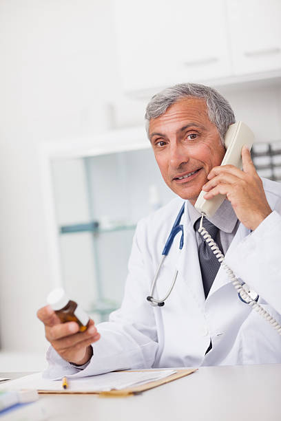 istock Doctor holding drug box and a phone while sitting 168810767