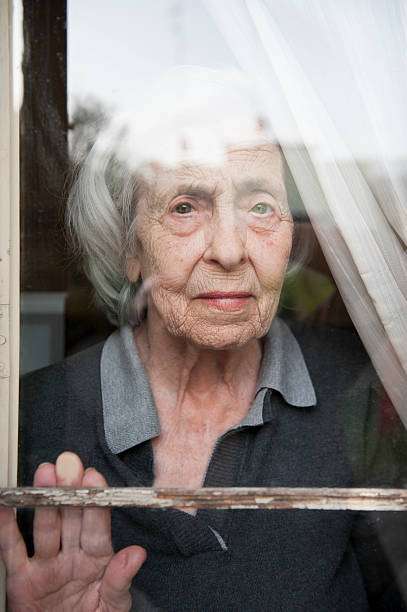 istock Senior woman looking through a window looking lonely 168816641