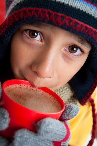 Close up of mixed raced boy holding red hot chocolate drink