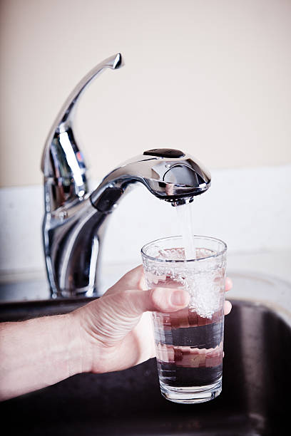 assetato uomo riempiendo un grande bicchiere d'acqua - thrist foto e immagini stock