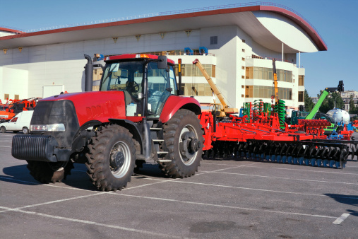 Closeup of modern red tractor for plough up on parking lot