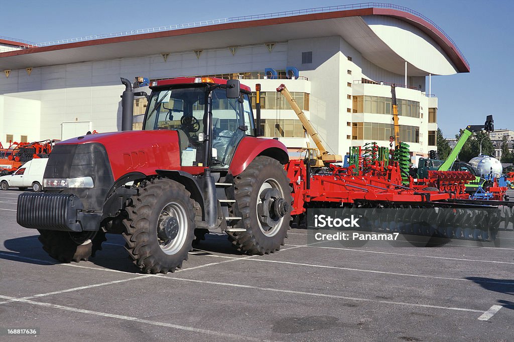 Wheeled modern tractor Closeup of modern red tractor for plough up on parking lot Agriculture Stock Photo
