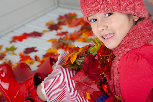 Happy 8 year old white girl sitting on autumn doorstep