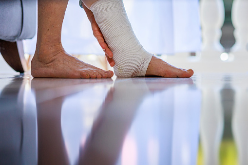 Close-up of a senior woman's leg with bandage to protect a sprained ankle and swollen foot