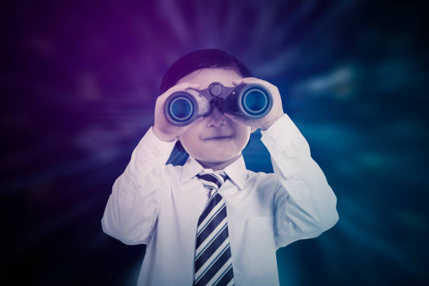 Cute Asian boy holding binoculars over blur background