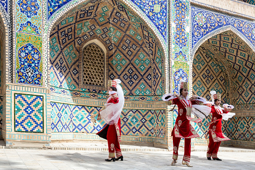 Uzbek female folk dancers in red national clothes. Travelling and culture. April 20, 2023 - Bukhara, Uzbekistan