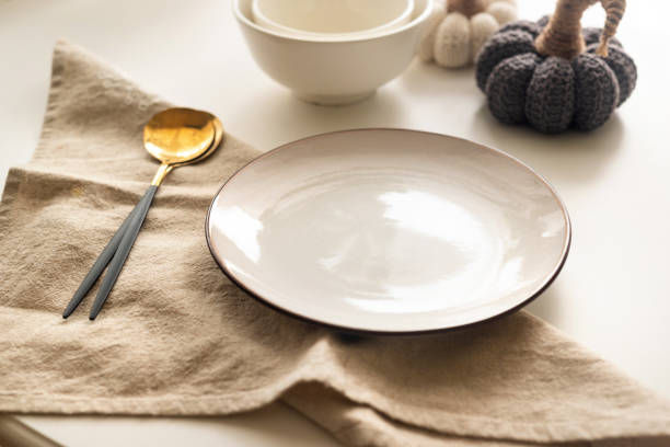 istock Dinner table setting with white plates and  decorative knite pumpkins on white table top view. 1688252384