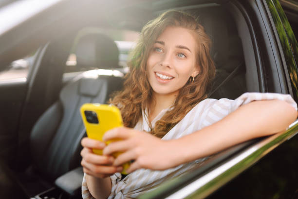 istock Beautiful female driver uses a smartphone in the car. 1688257510