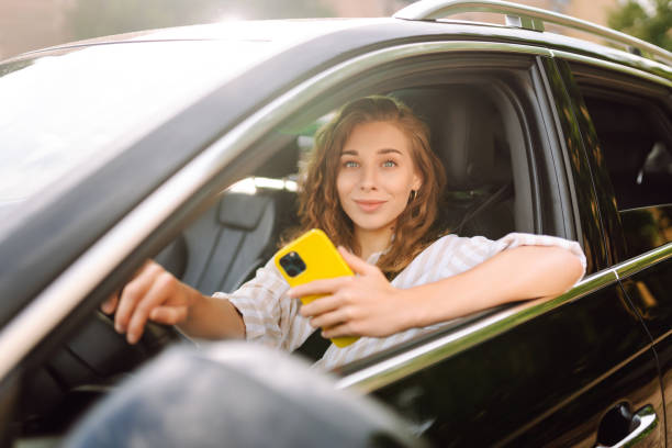 istock Beautiful female driver uses a smartphone in the car. 1688257515