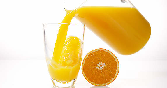 Pouring orange juice on white background.